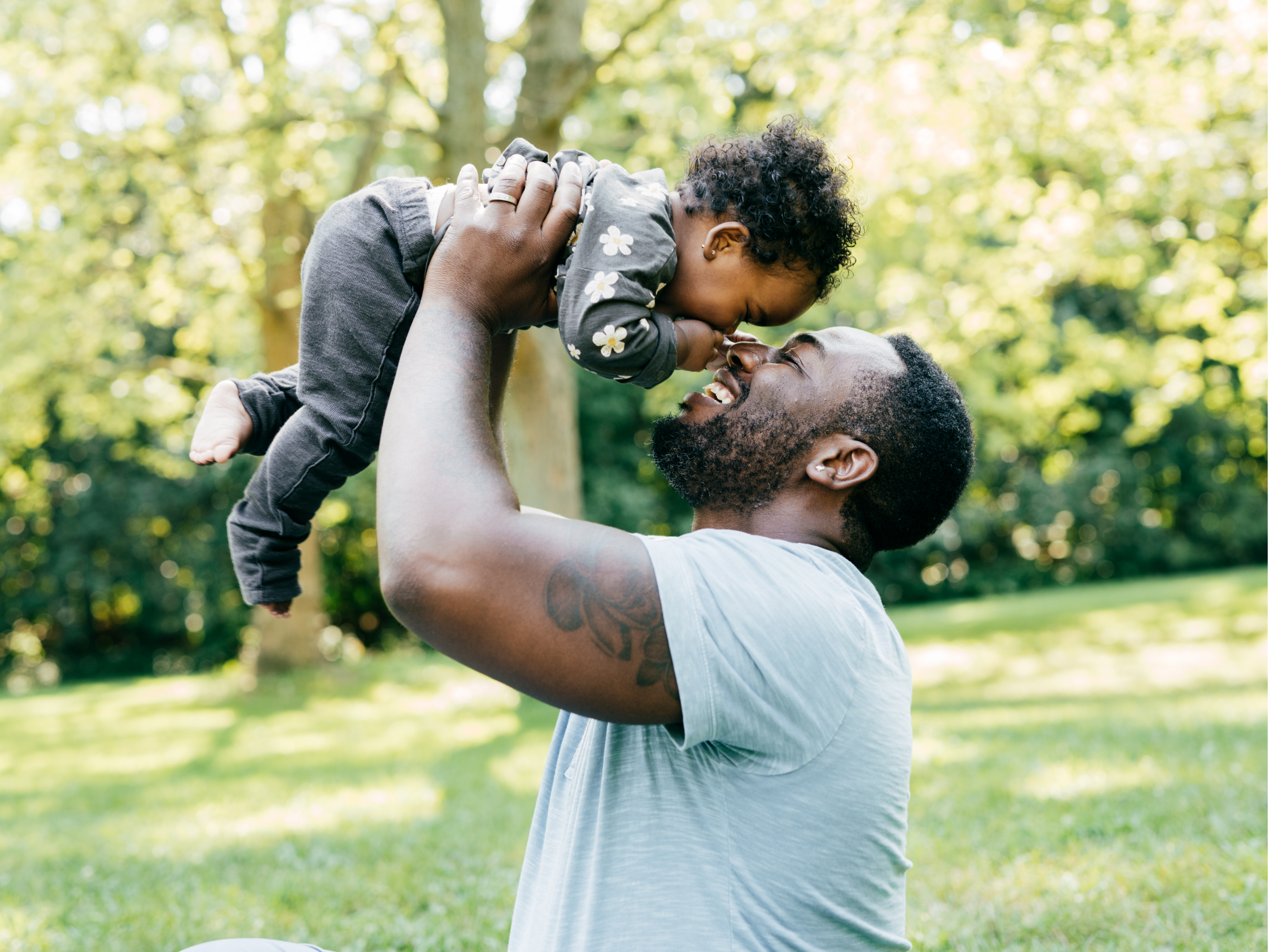 Father lifting baby in the air and smiling.