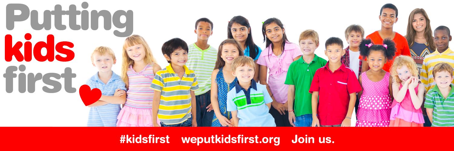 Group of kids with a sign that says "Putting Kids First".