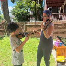 A musician and a child play violin together