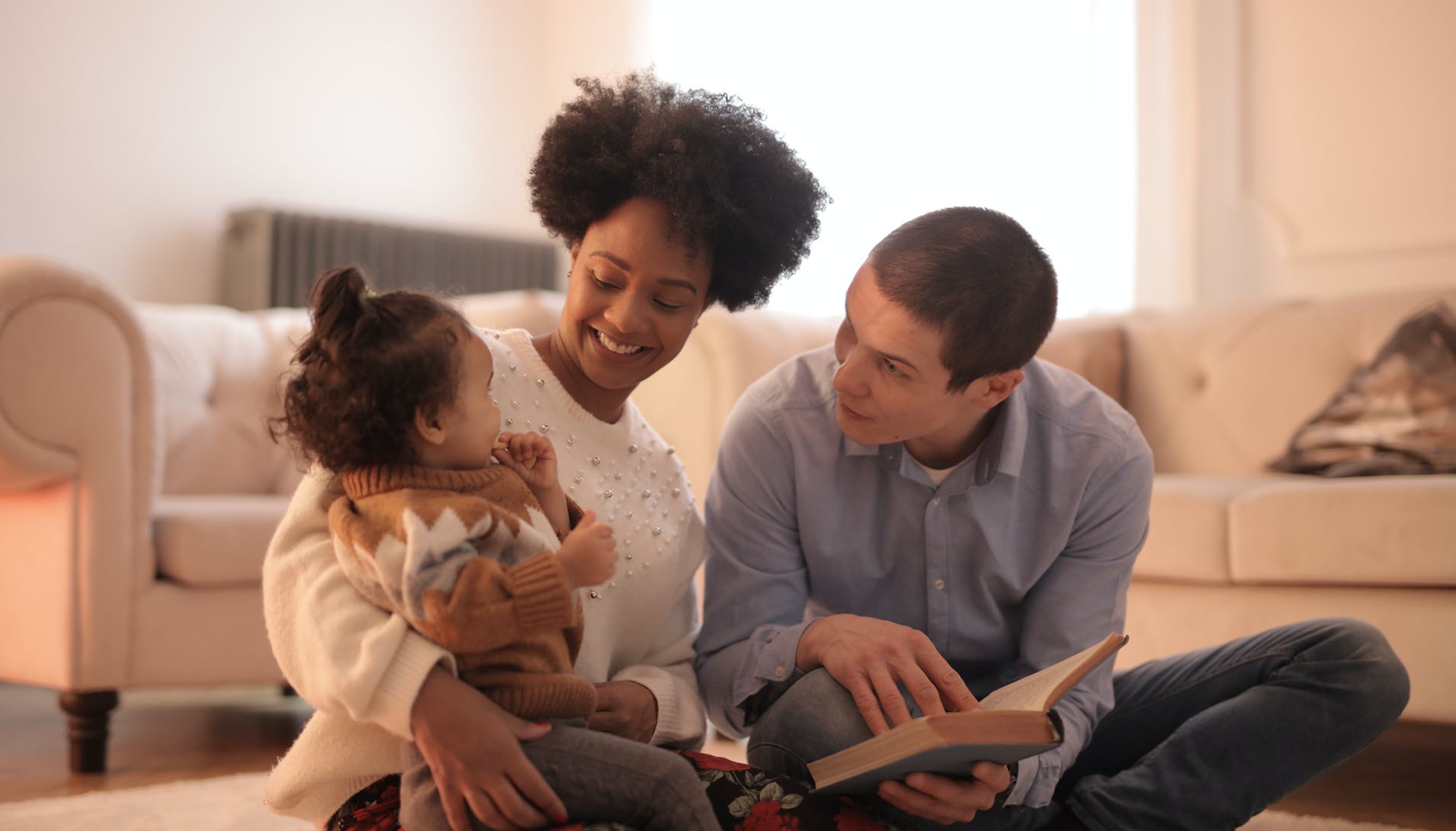 Two parents reading to their toddler.